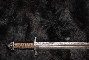 Old sword on the black beast skin concept flat lay background.
