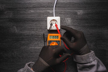 No mains voltage in the electric plug  concept. Electric voltmeter with zero on the display and hands of electrician. - obrazy, fototapety, plakaty