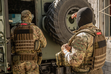 Fototapeta premium Military operations in Ukraine. A soldier with machine guns near an armored personnel carrier. The military repulse the attack of the invaders, hold the defense, capture the terrorists.