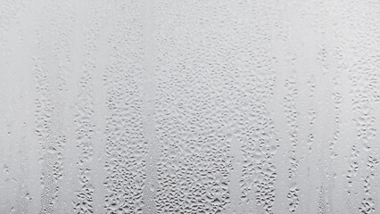 Close up water drop on grey background, misted glass with droplets of water draining down. Dripping...