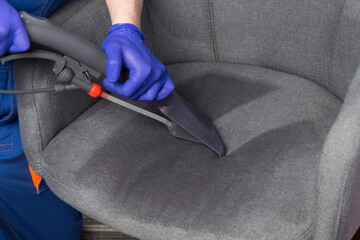 specialist, collects water with cleaning agent from the drapery of the chair with a cleaning vacuum...