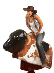 Woah. Studio shot of a beautiful young woman riding a mechanical bull against a white background.
