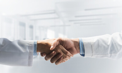 Close-up of the handshake between the two medics. Against the backdrop of the cityscape