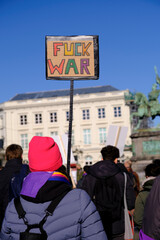 Fototapeta na wymiar Anonymous crowd protesting against war holding sign 'Fuck war'