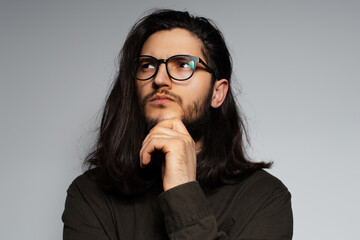 Studio portrait of young attractive thoughtful man with long hair.