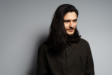 Studio portrait of young man with long hair on grey background.