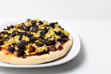 Homemade vegan pizza on white plate against white background.