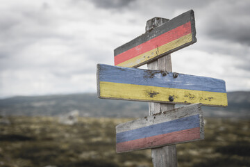 germany ukraine russia flag on wooden signpost outdoors in nature. Conflict in ukraine concept.