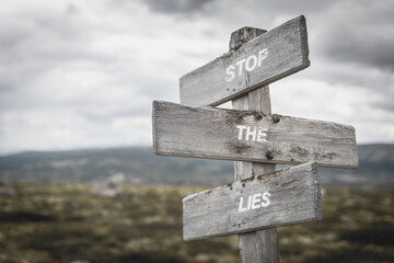 Stop the lies text quote on signpost outdoors in nature.