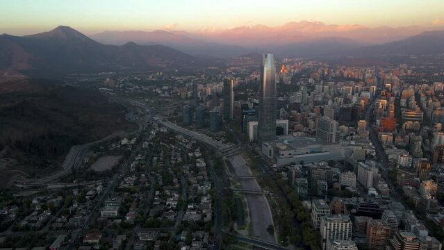 Aerial dolly in of modern Sanhattan skyscrapers, Mapocho river and El Plomo hill in background at blue hour, Santiago, Chile