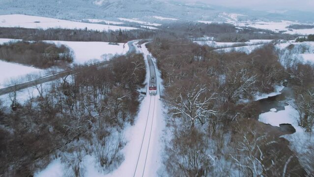 Aerial View Over Train Travelling Through Winter Snow Landscape At Tatra National Park. Drone flying over trains in Tatra national park Slovakia, sustainable travel