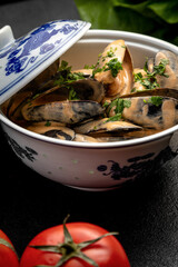 mussels in sauce in a ceramic dish on a dark decorated background