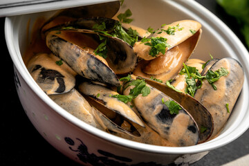 mussels in sauce in a ceramic dish on a dark decorated background