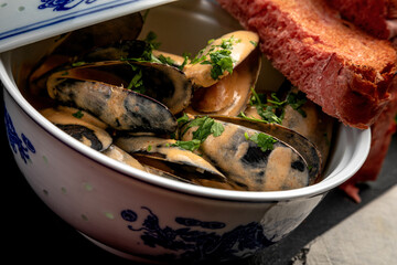 mussels in sauce in a ceramic dish on a dark decorated background
