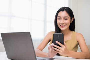 Young asian woman using smartphone chatting video conference online sitting in living room at home....