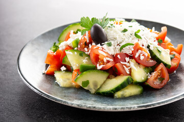 Traditional Bulgarian shopska salad with tomato,cucumber and bulgarian sirene cheese on black background