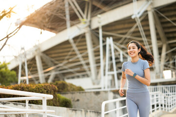 Fototapeta premium Attractive beautiful woman wearing sportswear running at sport stadium. Fit woman jogging outdoor. Workout exercise in the morning. Healthy and active lifestyle concept.