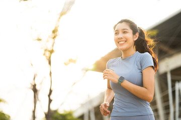 Attractive beautiful woman wearing sportswear running at sport stadium. Fit woman jogging outdoor. Workout exercise in the morning. Healthy and active lifestyle concept.