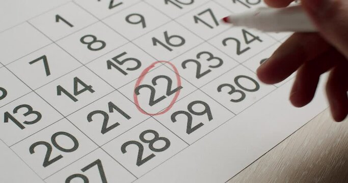 Wall Calendar 22th Date of the Month Crossed Out. Hand crosses out of the twenty two day on the paper calendar using a Red Pen. Very important date on the calendar. Signing a day on a calendar.