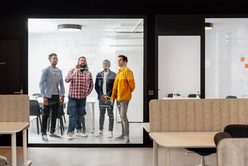 Fototapeta premium multiracial group of coworkers work in an office room drawing on a glass wall strategies for the success of the company. Brainstorming session.