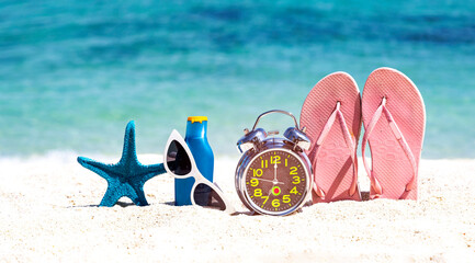 Alarm clock to summer a holiday and accessories on the beach background