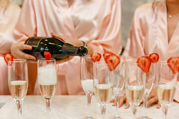 Morning of the bride Gorgeous bride with bridesmaids in pink robes are holding glasses and drinking...