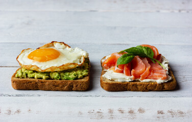 Two sandwiches with smoked salmon, cream cheese, avocado and fried egg. Concept for healthy breakfast.