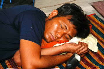 Worker Middle-aged Asian man relax sleeps easily due to exhaustion from overwork, sleeping on a mat...