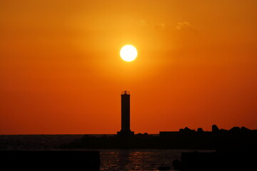 Fototapeta premium 灯台と沈む夕日 （高知県 室戸市 室戸岬漁港）