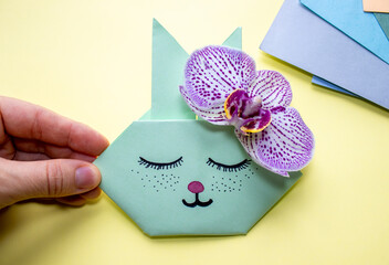 cute origami rabbit with chocolate eggs or on shopping pack or with purple orchid next to ear. easter holiday concept. sleeping bunny. 2023 year. do it yourself. art project.