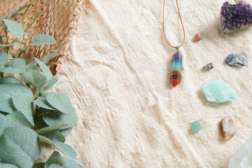 Backdrop or Flat lay background of raw stone and crystal, i.e. Amethyst, Amazonite, kayanite, 7 chakra pendant on linen cloth, green eucalyptus and old brown paper with copy space. beauty and nature.
