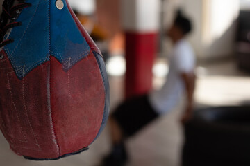 Boxing pear in the gym in focus and an out-of-focus boxer in the background