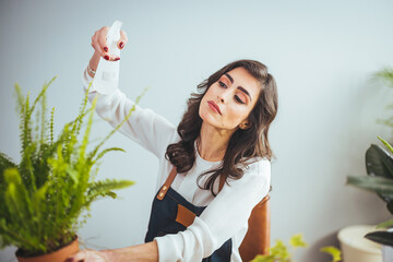 Woman takes care of the tree and is using a spray of water on a relaxing day in the garden at home. Woman hand spray on leave plants in the morning at home using a spray bottle watering houseplants