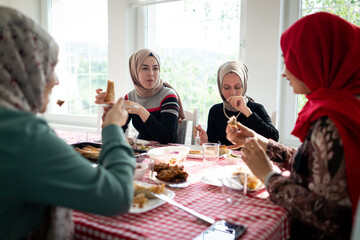 Muslim family and friends gathering together at home for eating dinner. High quality photo