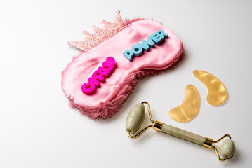 Sleep mask, facial roll-on, eye patches, and words: girl power. Flatlay. Concept of feminism and women's Day