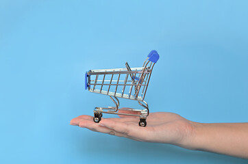 supermarket trolley on a blue background. Purchases. Minimalism. An empty shopping cart for the Buyer. The effect of online shopping.