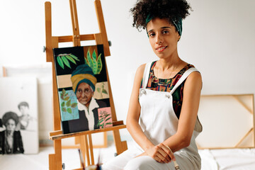 Confident young female painter sitting in her studio