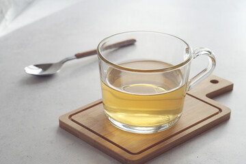Green tea (Chinese milk oolong) in a transparent mug on the table. Behind lies a teaspoon