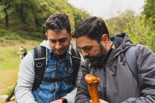 Dos chicos viendo la pantalla de una c&aacute;mara de fotos mientras hacen senderismo por ruta verde