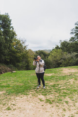 Mujer tomando fotos en paraje natural realizando senderismo