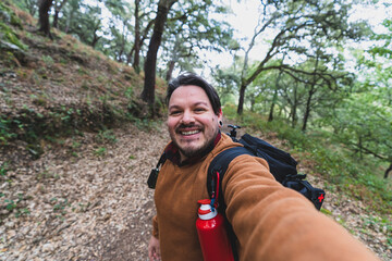 Autoretrato tipo selfie de un chico gordo en sendero de ruta verde con paisaje de bosque