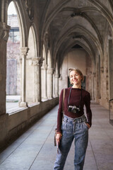 Portrait of blond female woman tourist with vintage camera visiting ancient monastery church in...