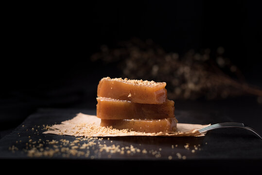 Dulce pasta de gelatina de membrillo dorado sobre una placa de madera negra	