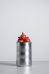 Tomates cherry enteros dentro de una lata de conservas sobre fondo gris - obrazy, fototapety, plakaty
