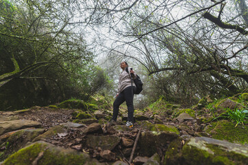 Naklejka premium Chica joven guapa en mitad de sendero de un bosque con niebla realizando senderismo