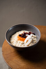 Healthy breakfast oatmeal porridge with coconut, dried cherries and melon puree in bowl. Warm porridge oats, vegan vegetarian weight loss dieting breakfast food