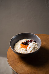 Healthy breakfast oatmeal porridge with coconut, dried cherries and melon puree in bowl. Warm porridge oats, vegan vegetarian weight loss dieting breakfast food