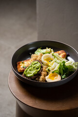 Plate with breakfast salads: avocado toast, egg, greens, fried cheese, quinoa