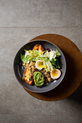 Plate with breakfast salads: avocado toast, egg, greens, fried cheese, quinoa