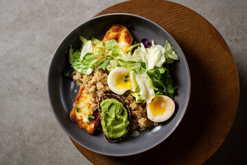 Plate with breakfast salads: avocado toast, egg, greens, fried cheese, quinoa